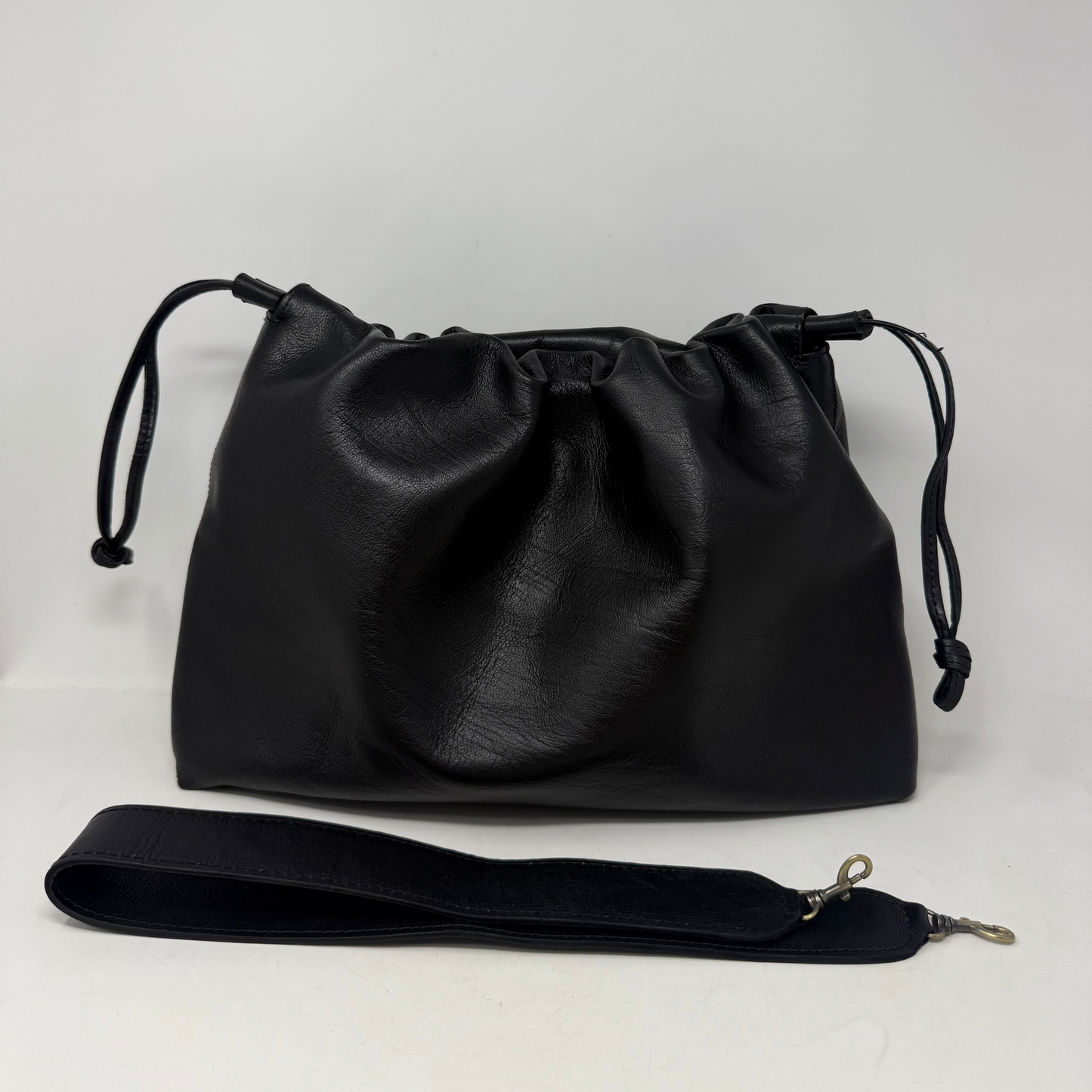 Black leather drawstring bag with a strap on a white background