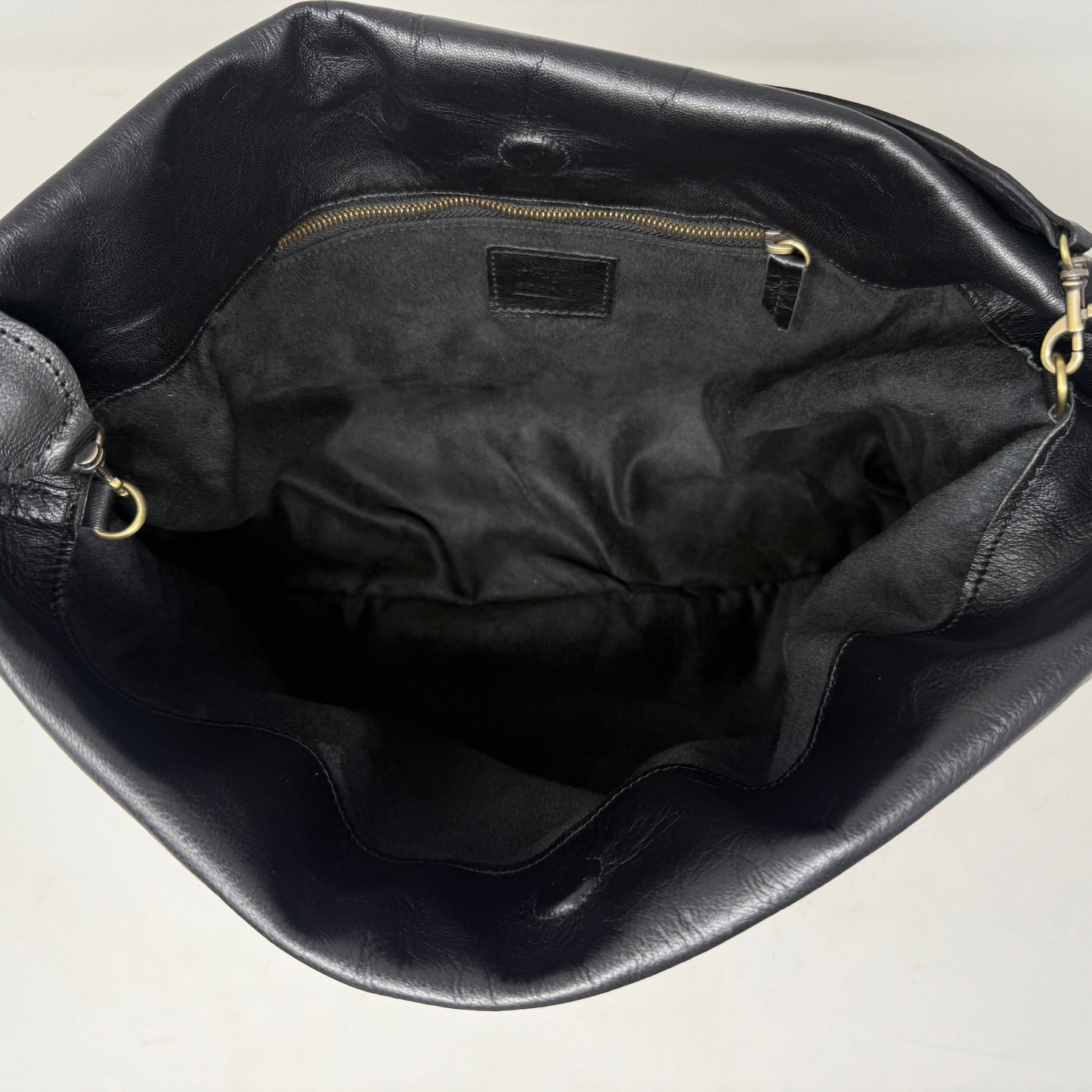 Black leather handbag with gold zipper on a light beige background