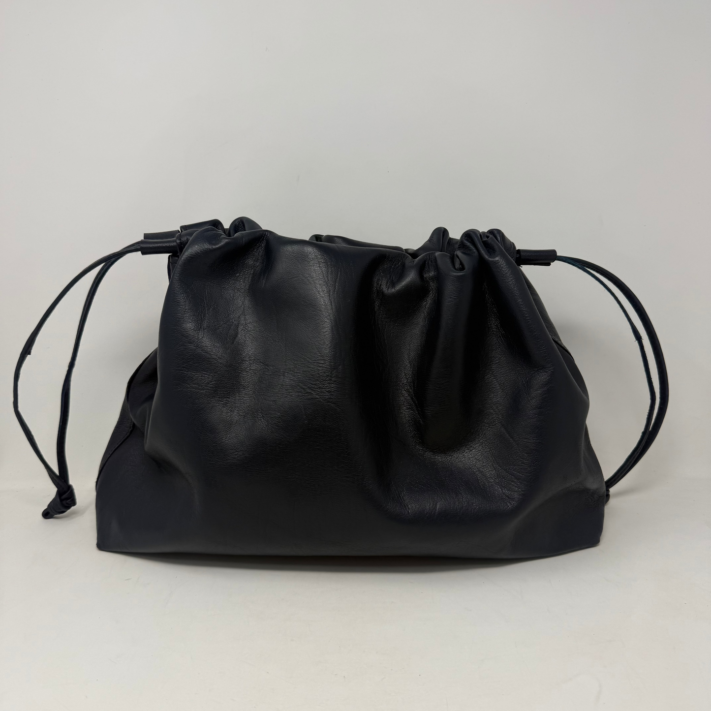 Black leather drawstring bag on a light gray background