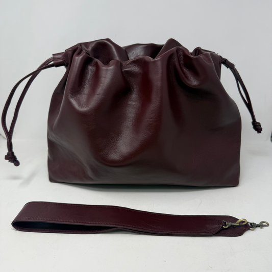 Brown leather drawstring bag with matching strap on a white background