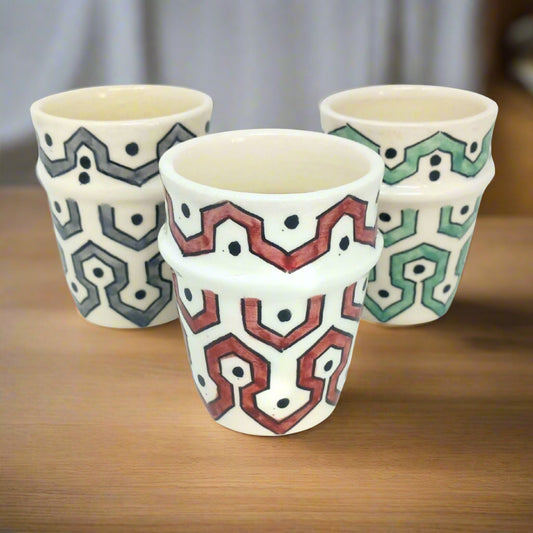 picture of three ceramic cups which have been fully handcrafted by artisans. In colours Burgundy red, mint Green and Grey.